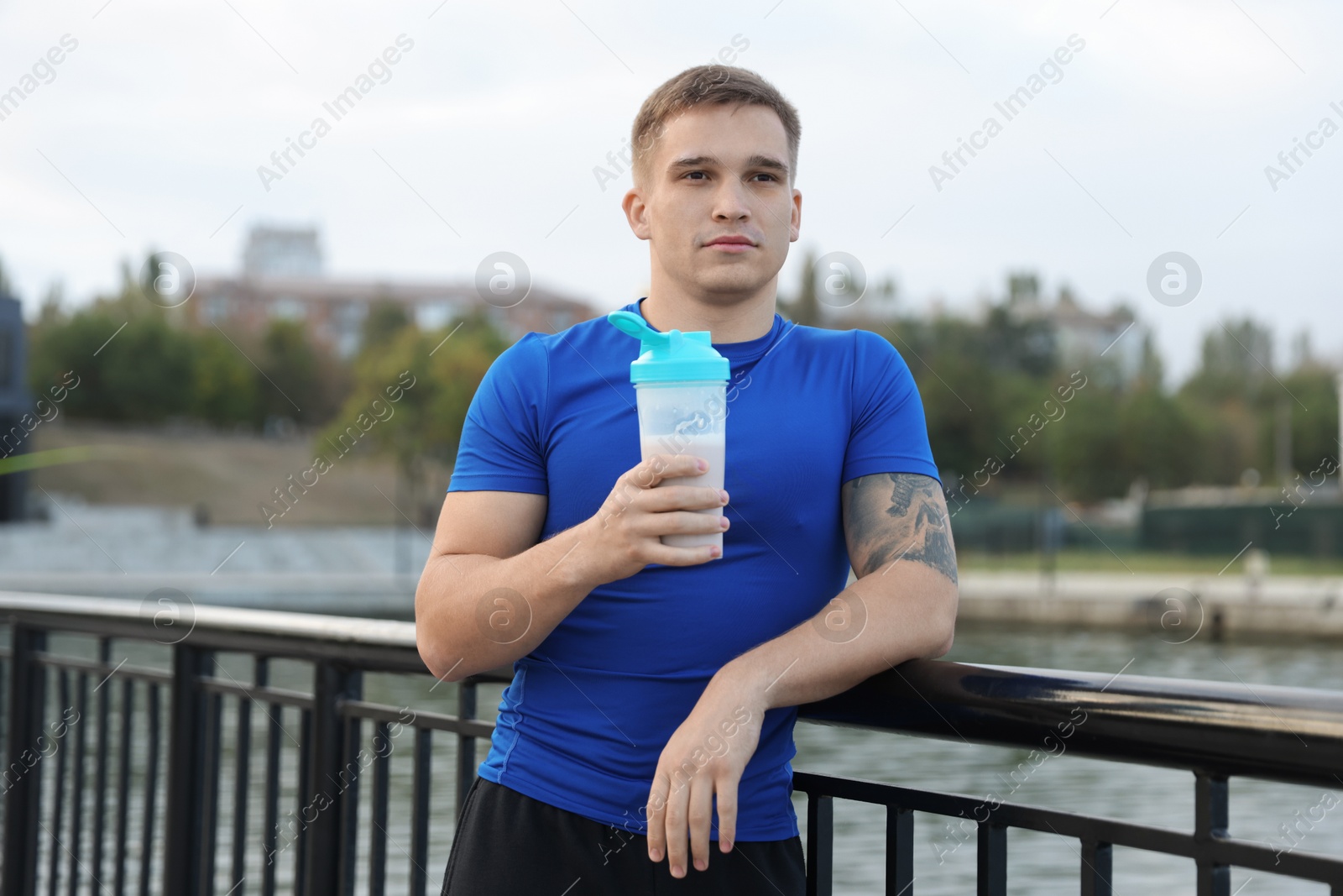 Photo of Athletic man with shaker of protein drink outdoors