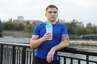 Photo of Athletic man with shaker of protein drink outdoors