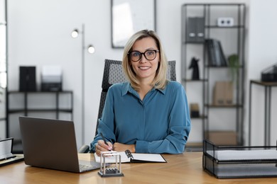 Photo of Happy businesswoman working at table in office