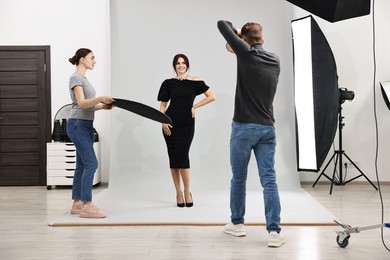 Photo of Photographer and assistant working with model in professional photo studio