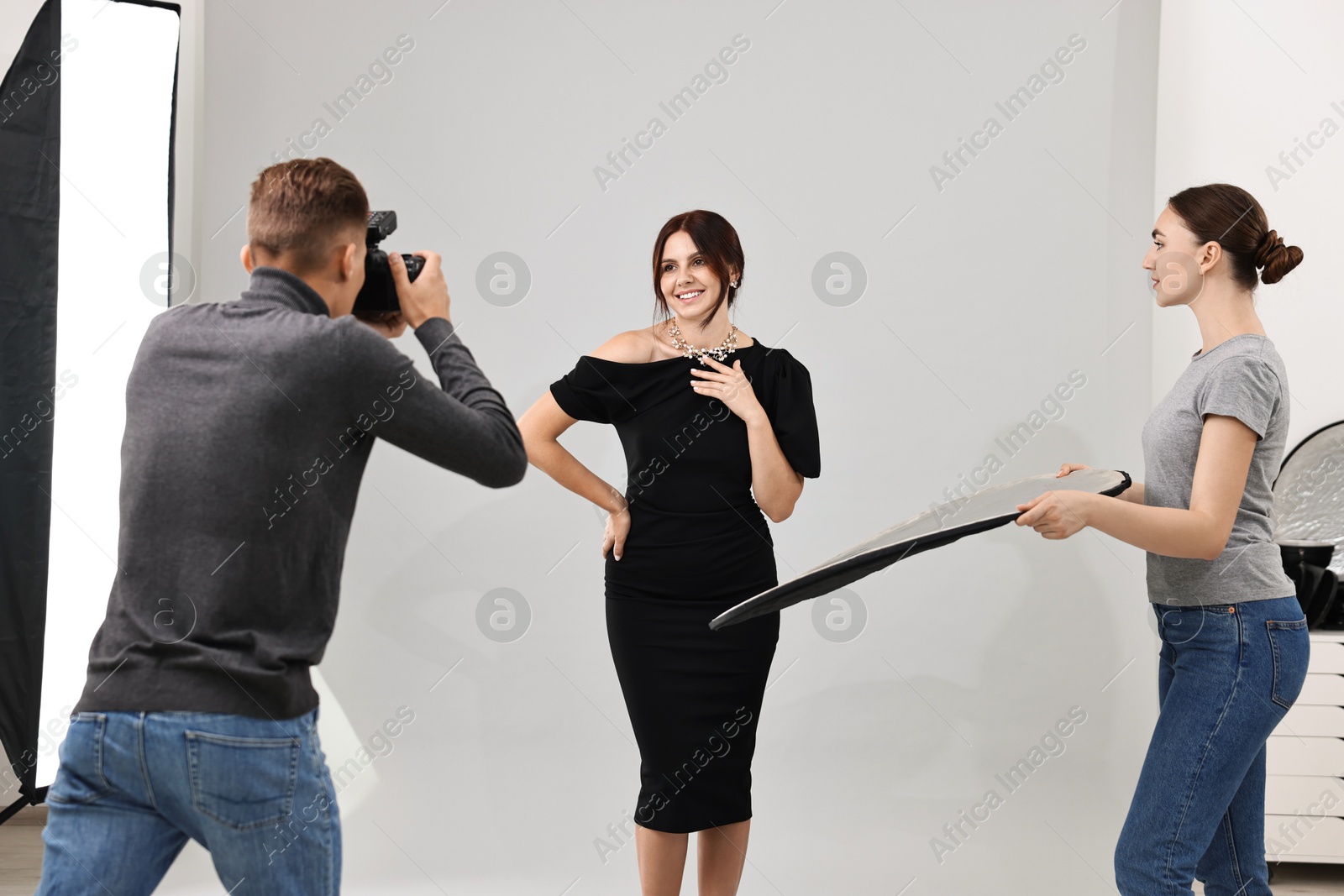 Photo of Photographer and assistant working with model in professional photo studio