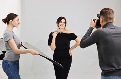 Photo of Photographer and assistant working with model in professional photo studio