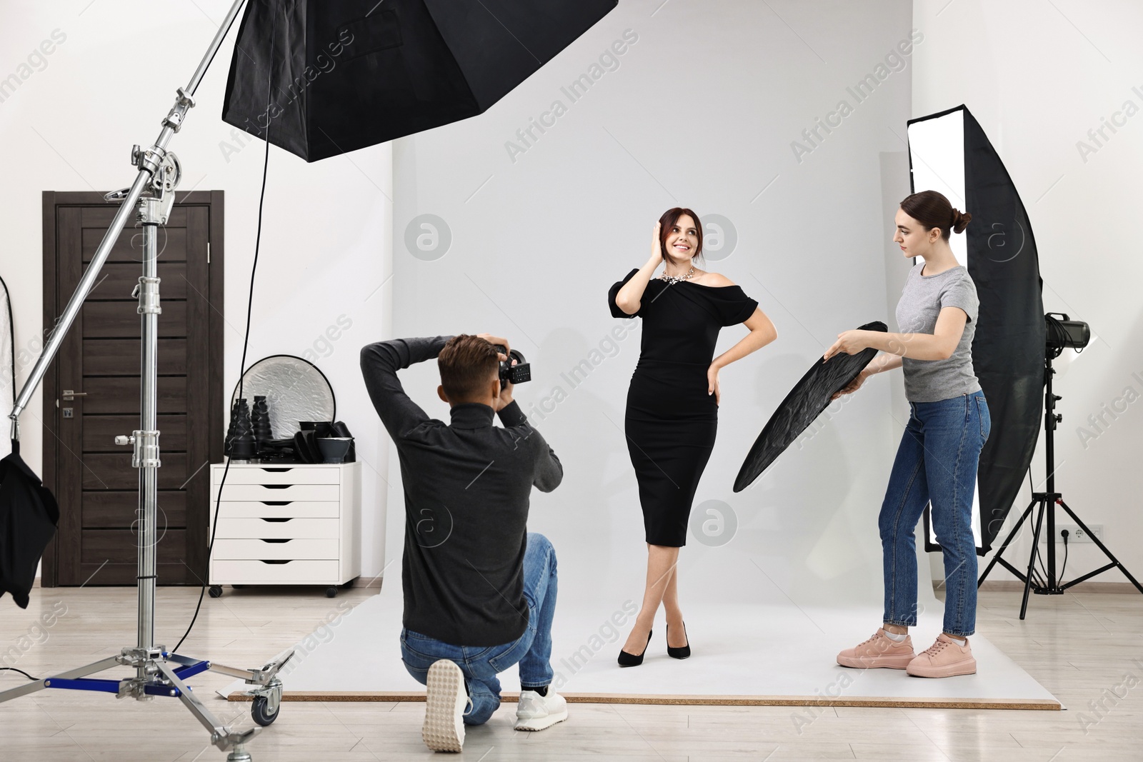 Photo of Photographer and assistant working with model in professional photo studio