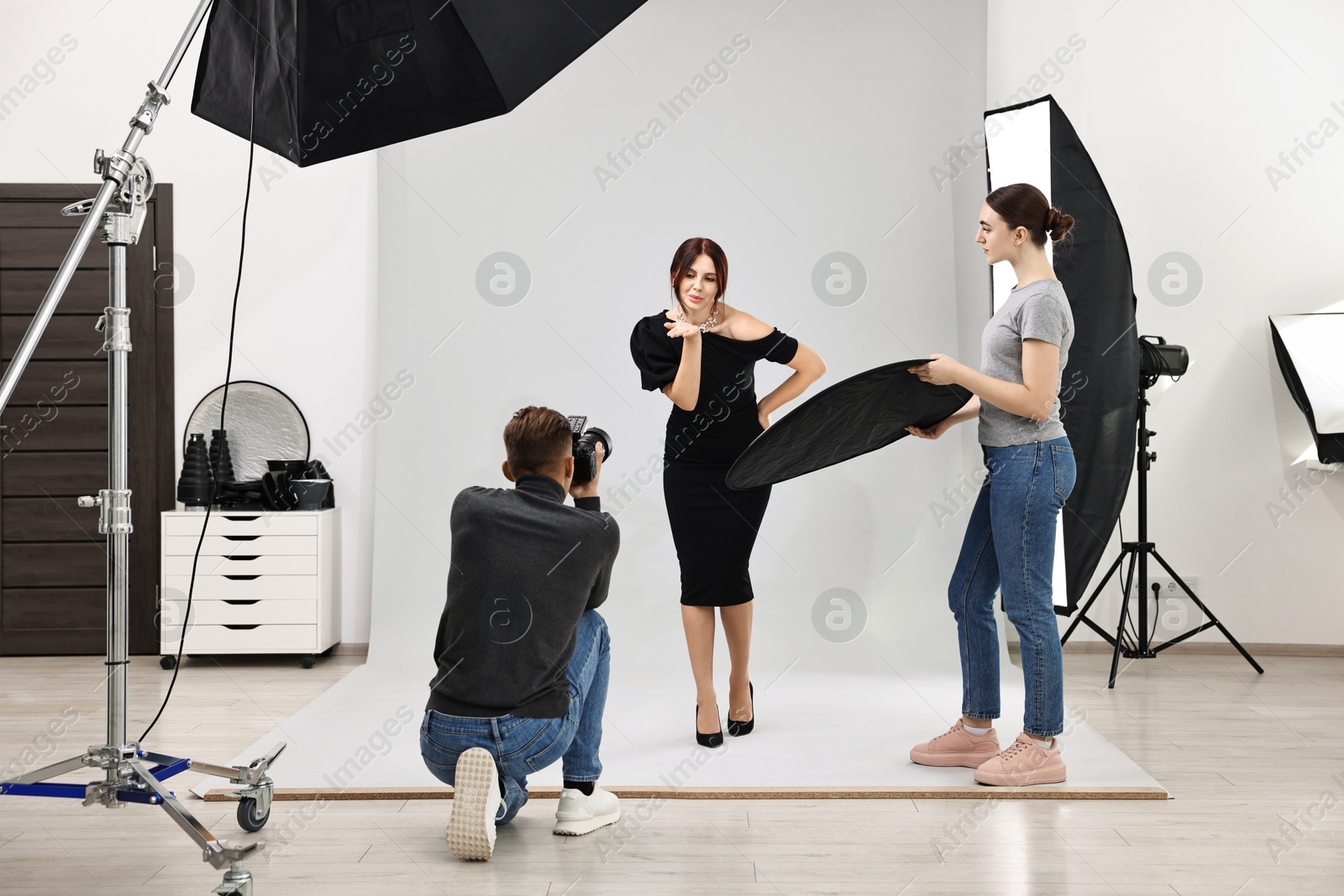 Photo of Photographer and assistant working with model in professional photo studio