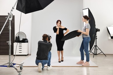 Photo of Photographer and assistant working with model in professional photo studio