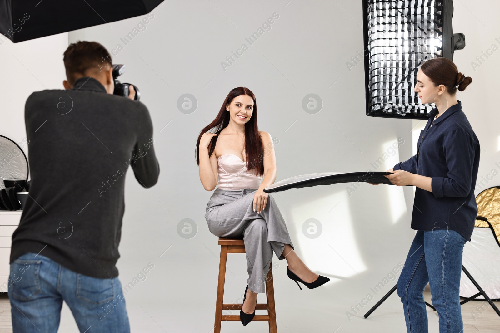 Photo of Photographer and assistant working with model in professional photo studio