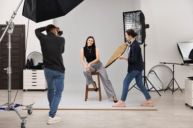 Photo of Photographer and assistant working with model in professional photo studio