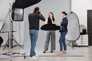 Photo of Photographer and assistant working with model in professional photo studio