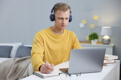 Photo of Student preparing for exam with laptop at table indoors