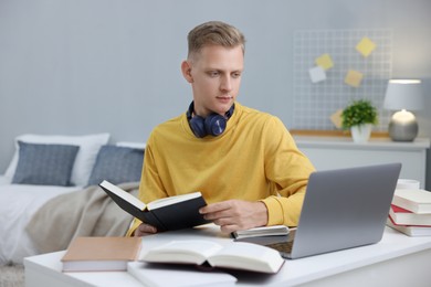 Student preparing for exam with laptop at table indoors