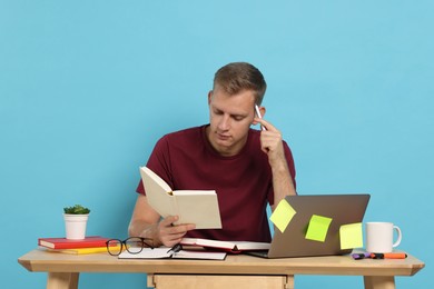 Photo of Student preparing for exam at table against light blue background