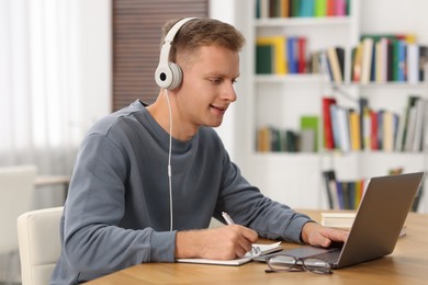 Photo of Student preparing for exam with laptop at table indoors