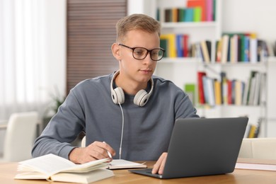 Photo of Student preparing for exam with laptop at table indoors