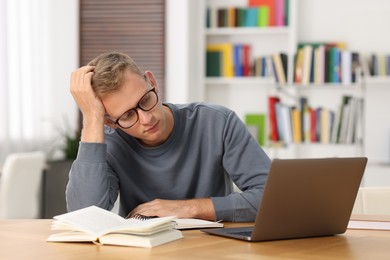 Photo of Student preparing for exam with laptop at table indoors