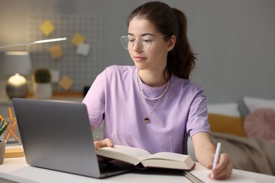 Photo of Student preparing for exam with laptop at table indoors