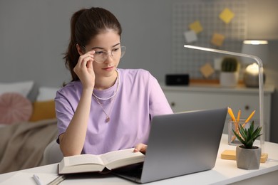 Photo of Student preparing for exam with laptop at table indoors