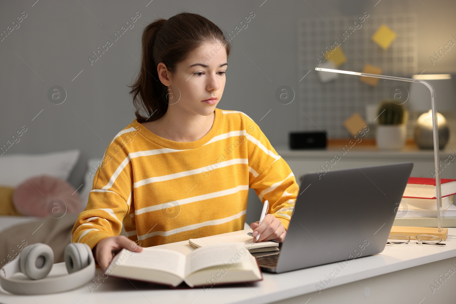 Photo of Student preparing for exam with laptop at table indoors