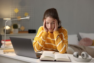 Photo of Tired student preparing for exam at table indoors