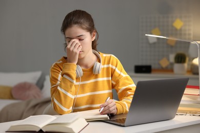 Tired student preparing for exam at table indoors