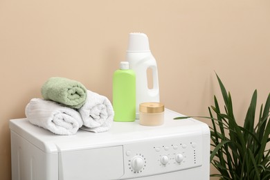 Photo of Laundry detergents and rolled towels on washing machine indoors