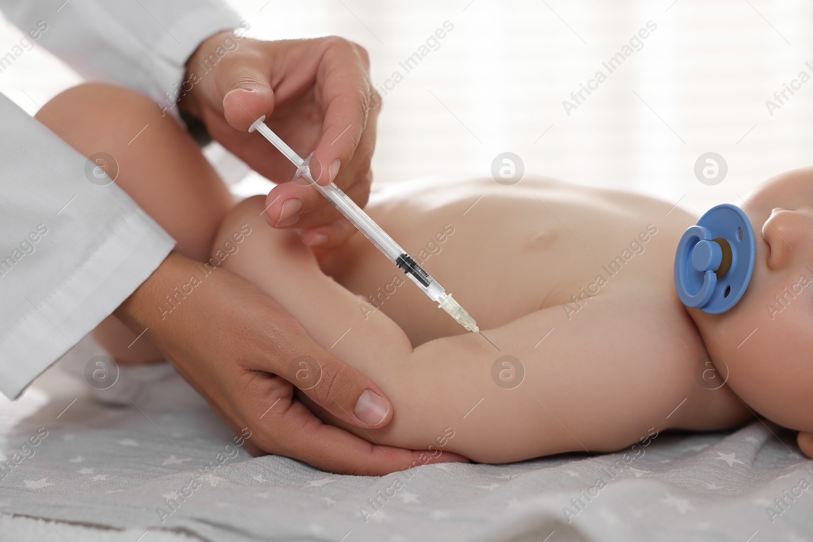 Photo of Pediatrician giving injection to baby in clinic, closeup