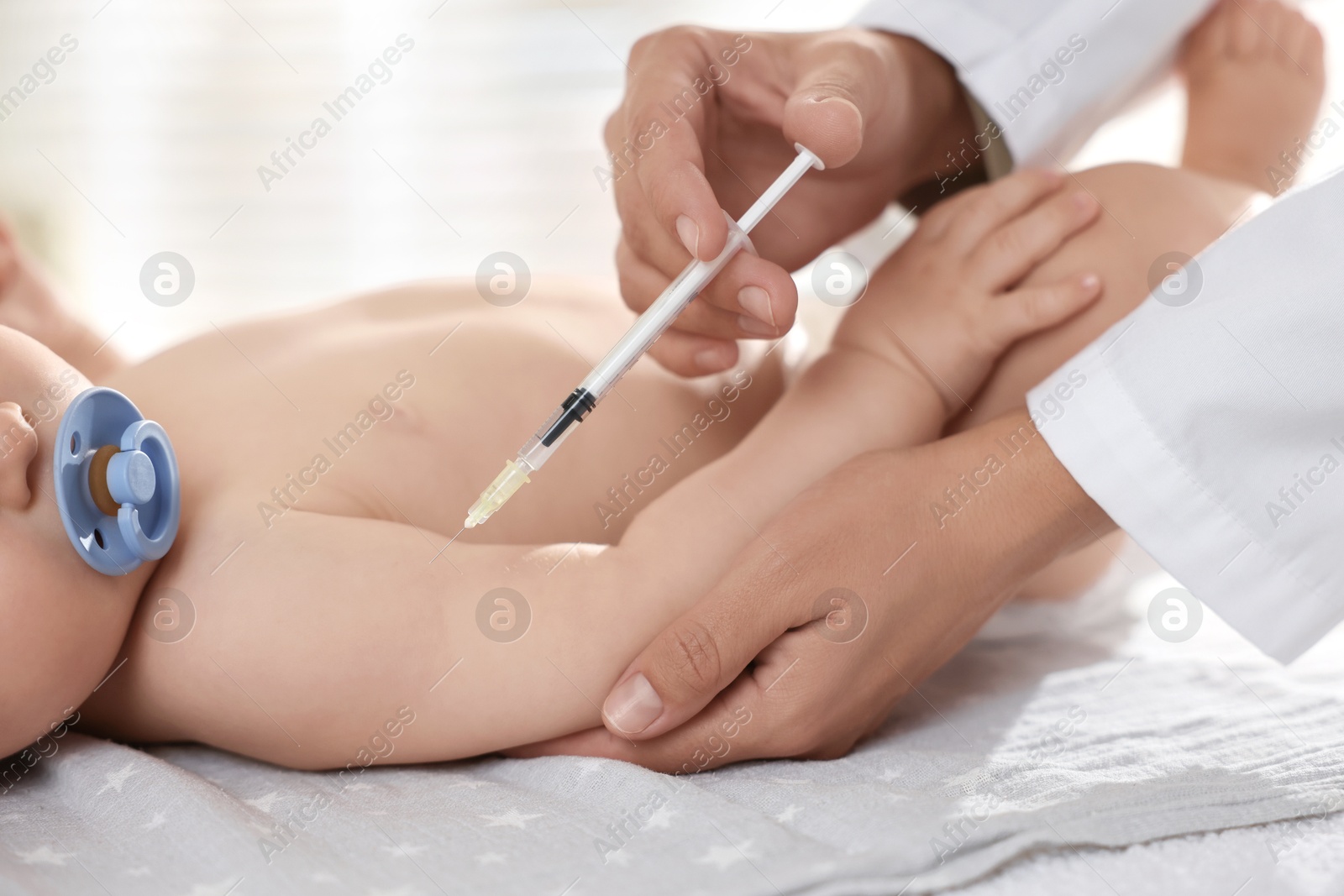 Photo of Pediatrician giving injection to baby in clinic, closeup