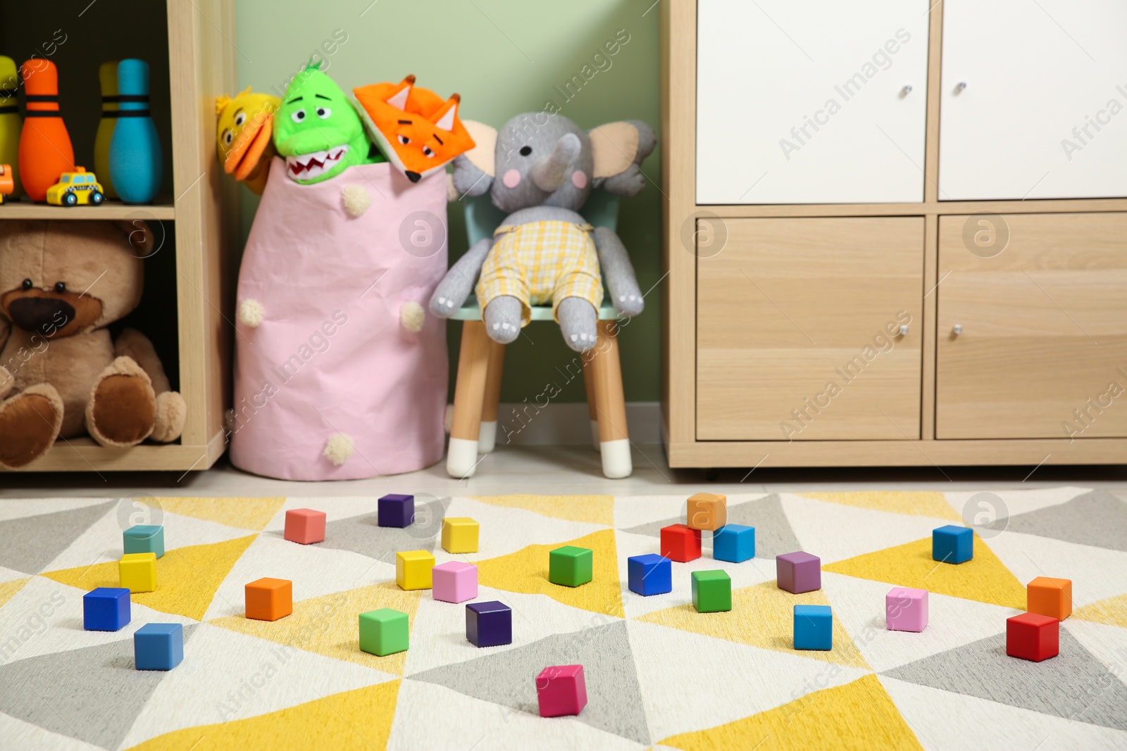 Photo of Colorful cubes on carpet and different toys in child's room