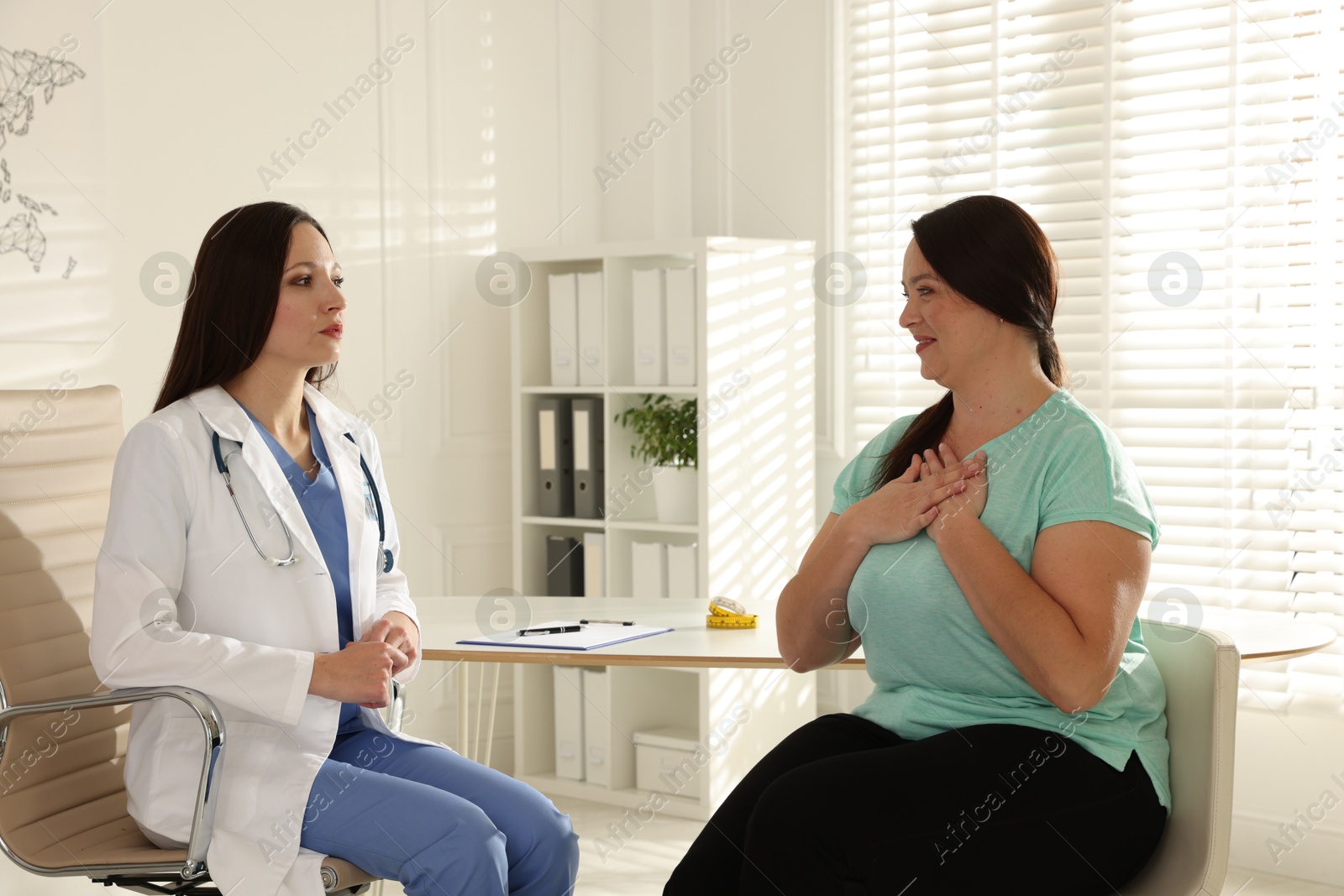 Photo of Nutritionist giving recommendations to overweight woman in hospital