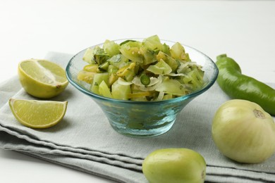 Photo of Delicious salsa (Pico de gallo) in bowl and products on white table, closeup