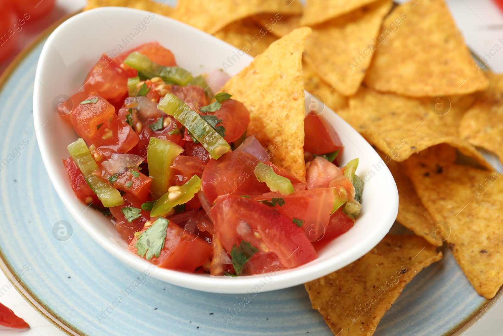 Photo of Delicious salsa (Pico de gallo) served with nachos on table, closeup