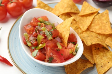 Photo of Delicious salsa (Pico de gallo) served with nachos and products on white table, closeup