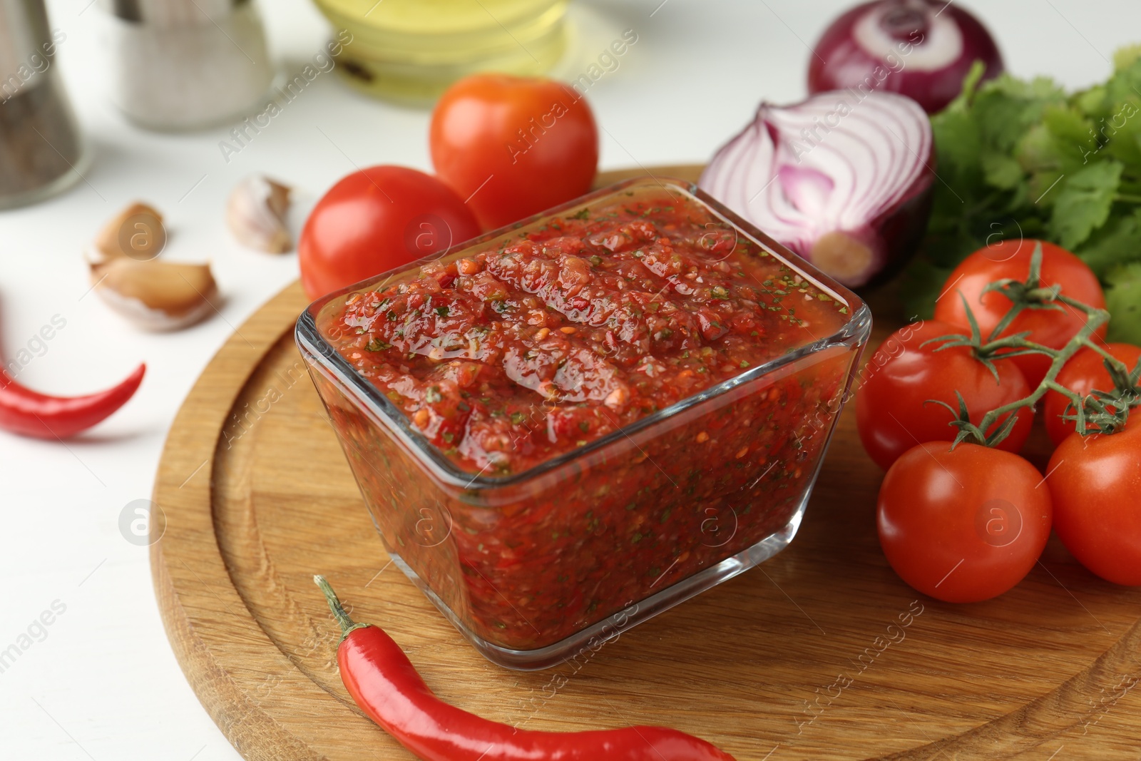 Photo of Delicious salsa sauce and ingredients on white table, closeup