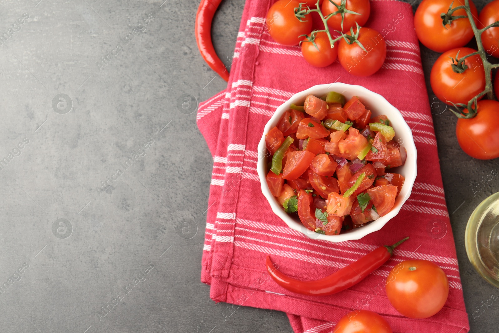 Photo of Delicious salsa (Pico de gallo) in bowl and ingredients on grey textured table, flat lay. Space for text