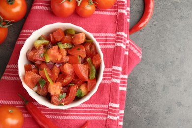 Photo of Delicious salsa (Pico de gallo) in bowl and ingredients on grey textured table, flat lay. Space for text