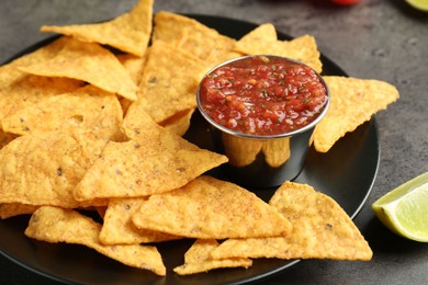 Photo of Delicious salsa sauce served with nachos on grey textured table, closeup