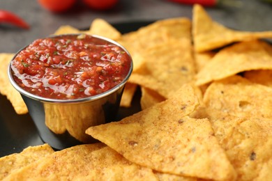 Photo of Delicious salsa sauce served with nachos on grey table, closeup