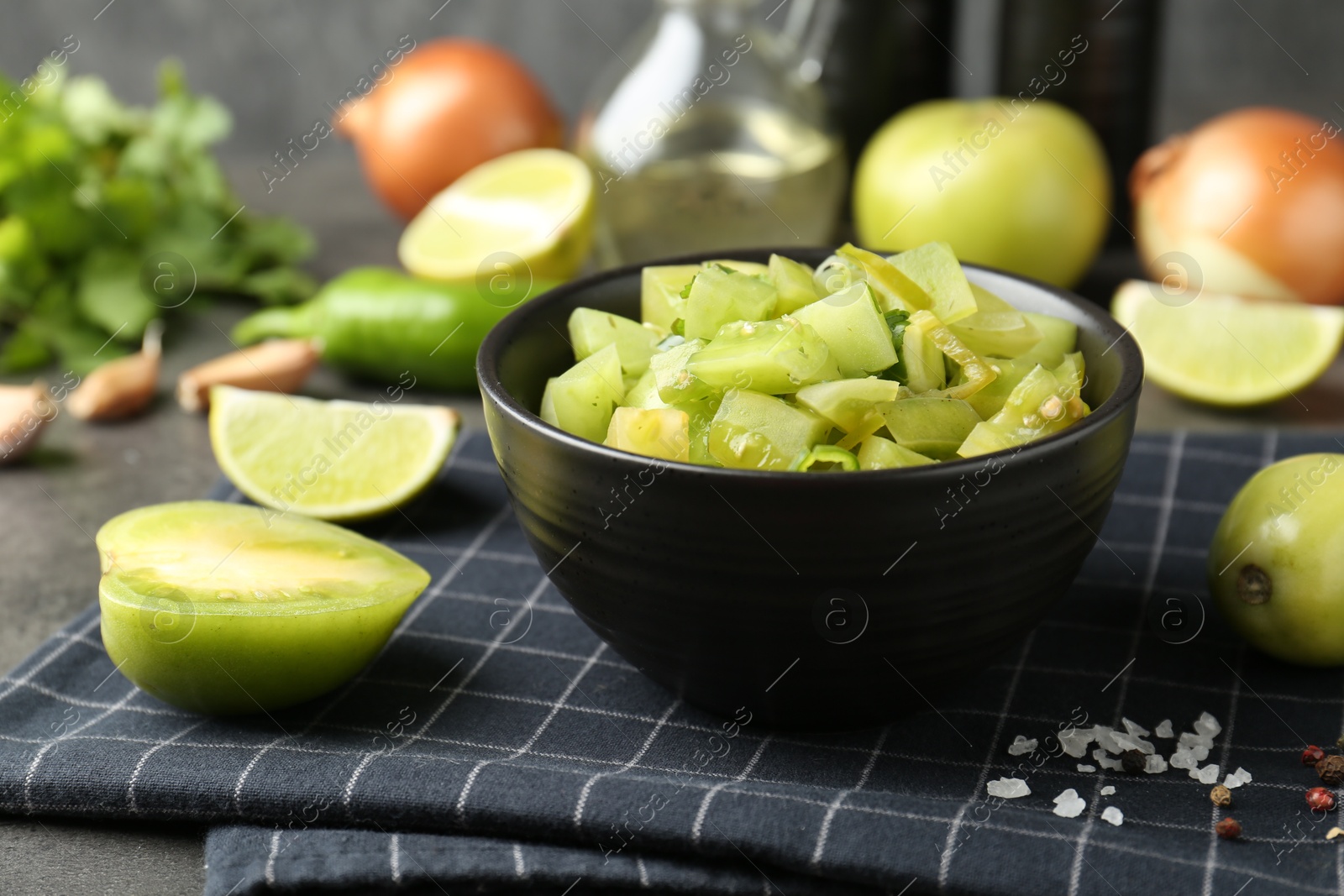 Photo of Delicious salsa (Pico de gallo) in bowl and products on grey table, closeup