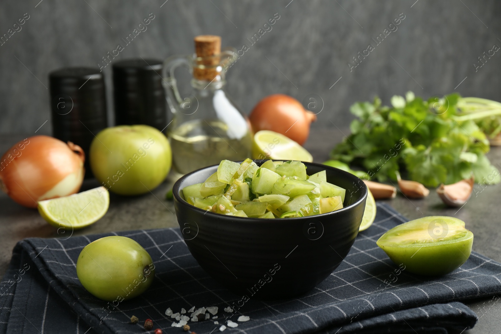 Photo of Delicious salsa (Pico de gallo) in bowl and products on grey table, closeup