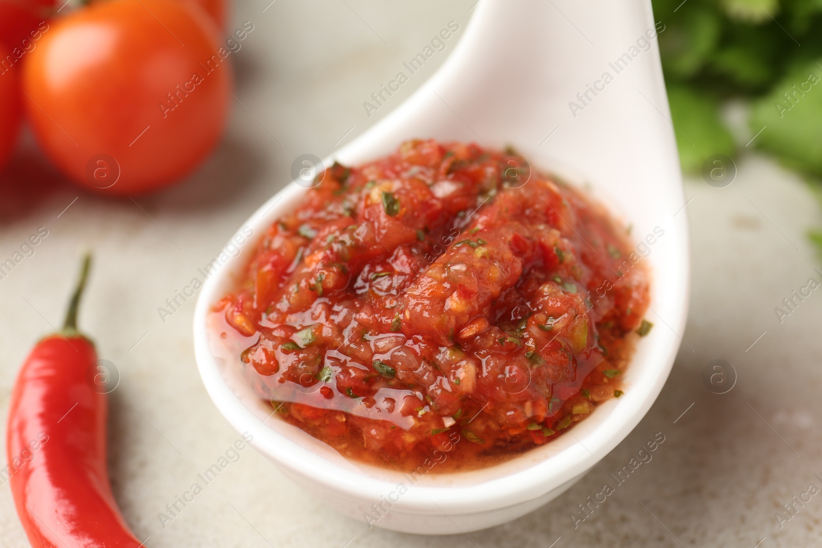 Photo of Delicious salsa sauce and chili pepper on light table, closeup