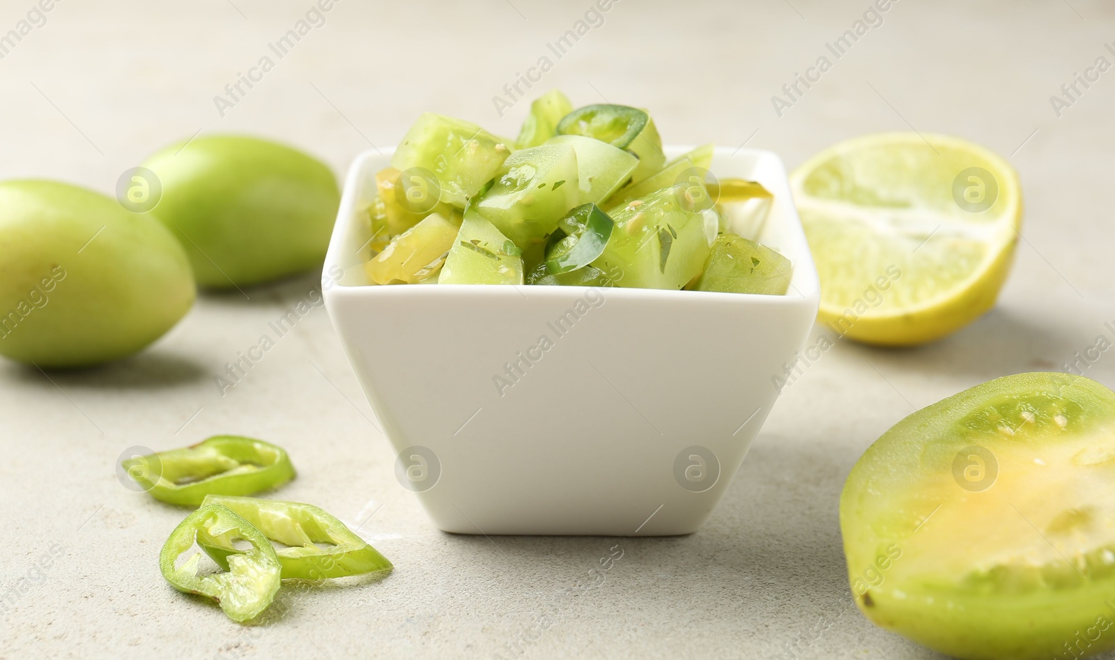 Photo of Delicious salsa (Pico de gallo) in bowl and products on light textured table, closeup