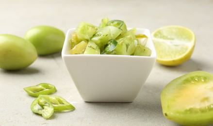 Photo of Delicious salsa (Pico de gallo) in bowl and products on light textured table, closeup