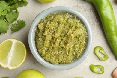 Photo of Delicious salsa sauce in bowl and ingredients on light textured table, flat lay