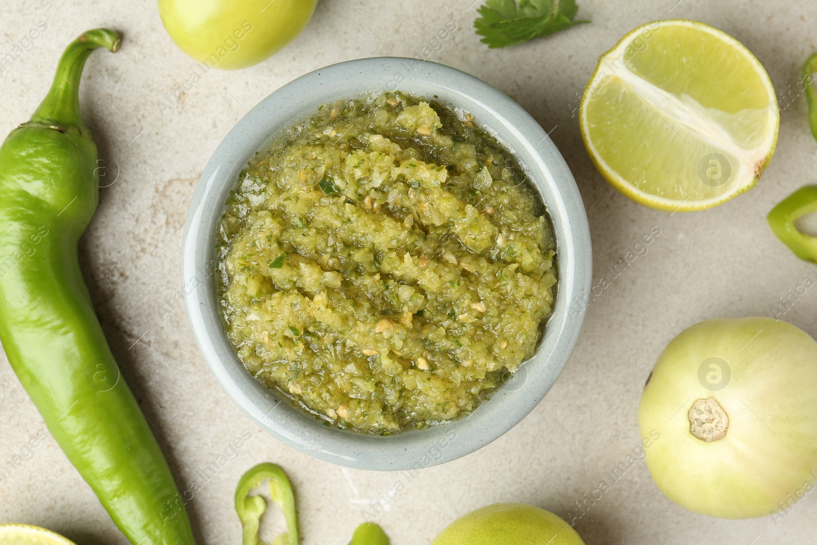 Photo of Delicious salsa sauce in bowl and ingredients on light textured table, flat lay