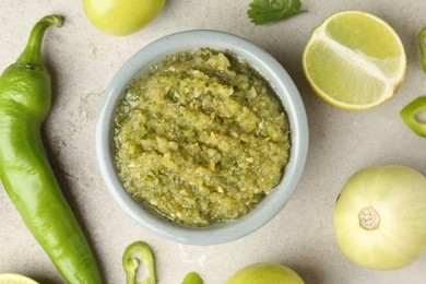 Photo of Delicious salsa sauce in bowl and ingredients on light textured table, flat lay