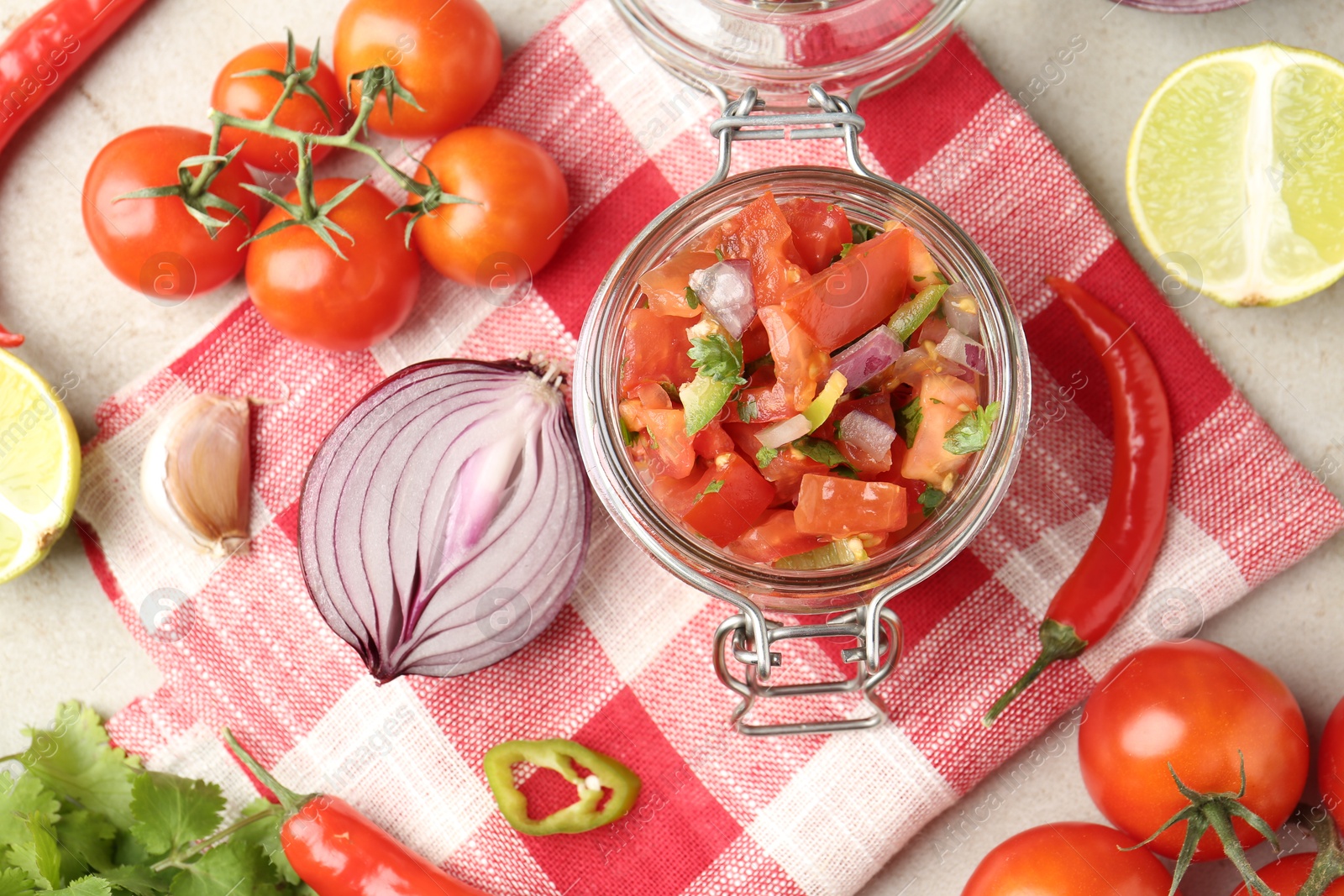 Photo of Delicious salsa (Pico de gallo) in jar and ingredients on light textured table, flat lay