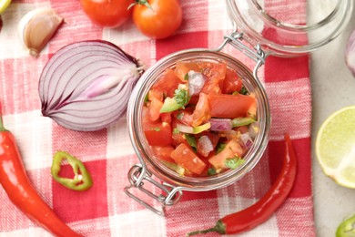 Photo of Delicious salsa (Pico de gallo) in jar and ingredients on table, flat lay