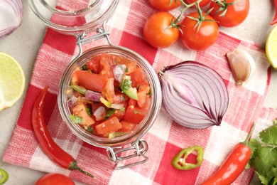 Photo of Delicious salsa (Pico de gallo) in jar and ingredients on table, flat lay