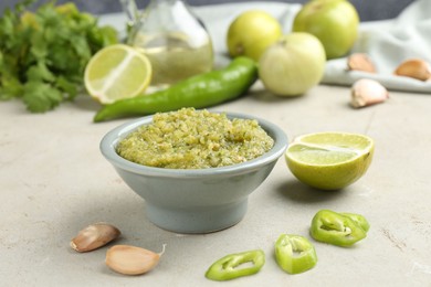 Photo of Delicious salsa sauce in bowl and products on light textured table, closeup