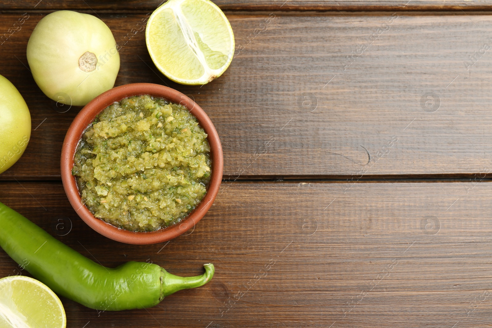 Photo of Delicious salsa sauce in bowl and products on wooden table, flat lay. Space for text