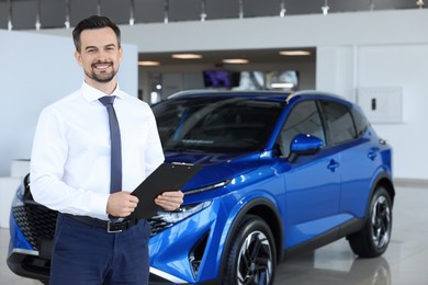 Photo of Happy salesman near new blue car in salon